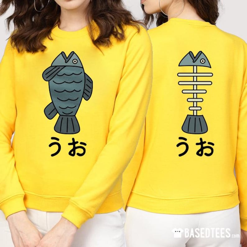 May include: Yellow sweatshirt with a cartoon fish on the front and a fish skeleton on the back. The text "うお" is printed below each image.