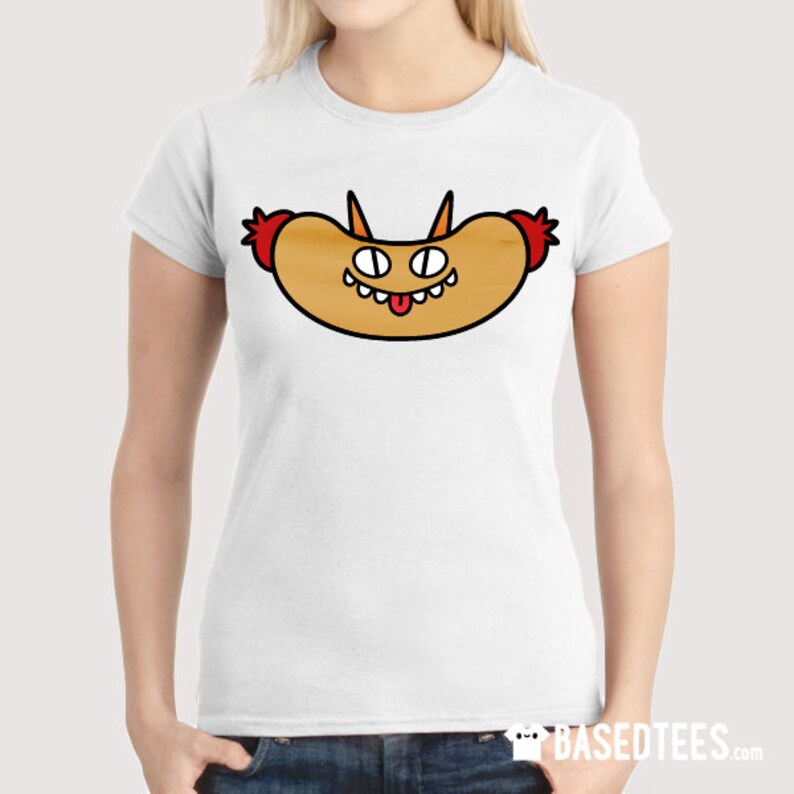 May include: White t-shirt featuring a cartoon hot dog character with a smiling face, horns, and red accents. The hot dog has a light brown bun, black outlines, and a playful design. The shirt is a casual wear item.