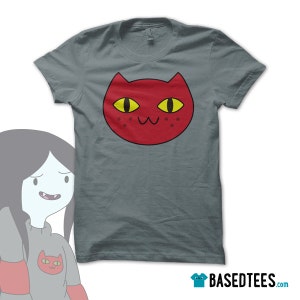 May include: A gray t-shirt with a red cat face graphic. The cat has yellow eyes and a pink nose. The cat's mouth is open in a smile, showing two small teeth.