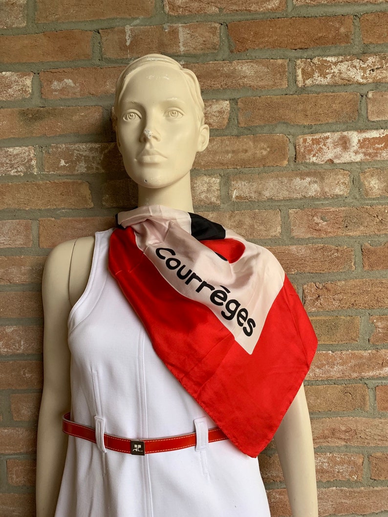 Puede incluir: Maniqu&iacute; con un vestido blanco, un cintur&oacute;n rojo y un pa&ntilde;uelo de seda. El pa&ntilde;uelo es rojo, negro y blanco con la palabra "Courr&egrave;ges" impresa. El cintur&oacute;n es rojo con una hebilla plateada.