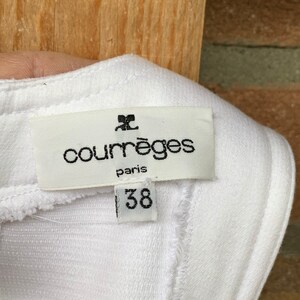 Puede incluir: Etiqueta de tela blanca con el nombre de la marca "courr&egrave;ges paris" en fuente negra. Debajo del nombre de la marca est&aacute; el n&uacute;mero "38" en fuente negra. La etiqueta est&aacute; adherida a tela blanca.