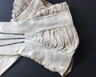 Vintage handschoenen van fijn ivoorkleurig leer uit het begin van de twintigste eeuw, met zwarte, witte en zwarte stiksels.