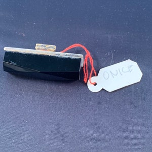 Può includere: Un ciondolo in onice nero con una montatura in argento. Il ciondolo è attaccato a uno spago rosso e ha un'etichetta bianca con la parola "ONICE" scritta su di essa.