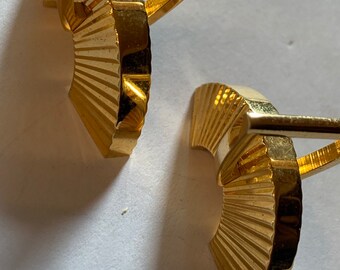 May include: A pair of gold cufflinks with a fan-shaped design. The cufflinks are made of metal and have a polished finish.