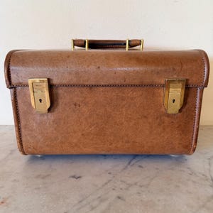 Estuche de viaje Gucci de piel de pecarí con doble cierre de latón y llave G escultural. Fabricado en Florencia, Italia, década de 1970. De segunda mano. Excelente estado.