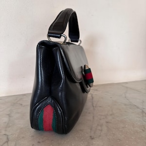 Sac Gucci Vintage en cuir de veau noir brossé avec poignée supérieure, empiècement en toile Web et doublure en cuir rouge, fabriqué en Italie dans les années 1960.