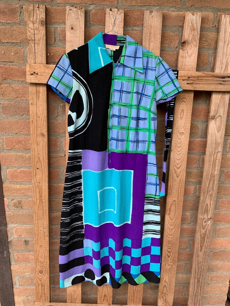 Puede incluir: Un vestido colorido con estampado geom&eacute;trico, manga corta y cuello. El vestido est&aacute; hecho de una tela ligera y tiene un lazo en la cintura.