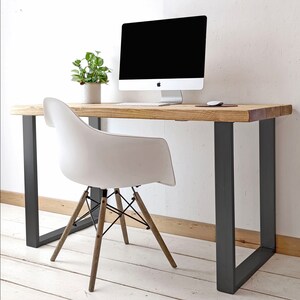 May include: A white desk chair with wooden legs sits in front of a wooden desk with black metal legs. A computer monitor is on the desk.