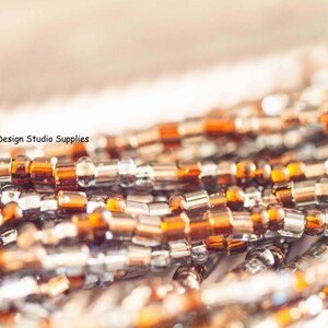 May include: Close-up of a strand of brown and silver beads. The beads are small and round, and they are arranged in a random pattern.