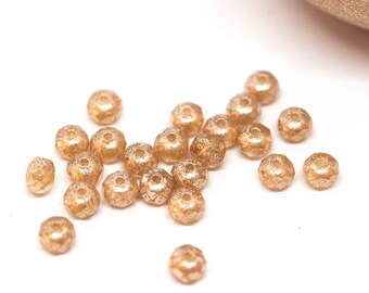 May include: A scattering of small, gold-colored, faceted glass beads. The beads have a slightly iridescent finish.