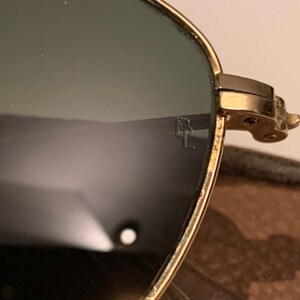Peut inclure: Lunettes de soleil aviateur dor&eacute;es avec des verres verts. Les lunettes ont une monture en m&eacute;tal et sont en bon &eacute;tat.