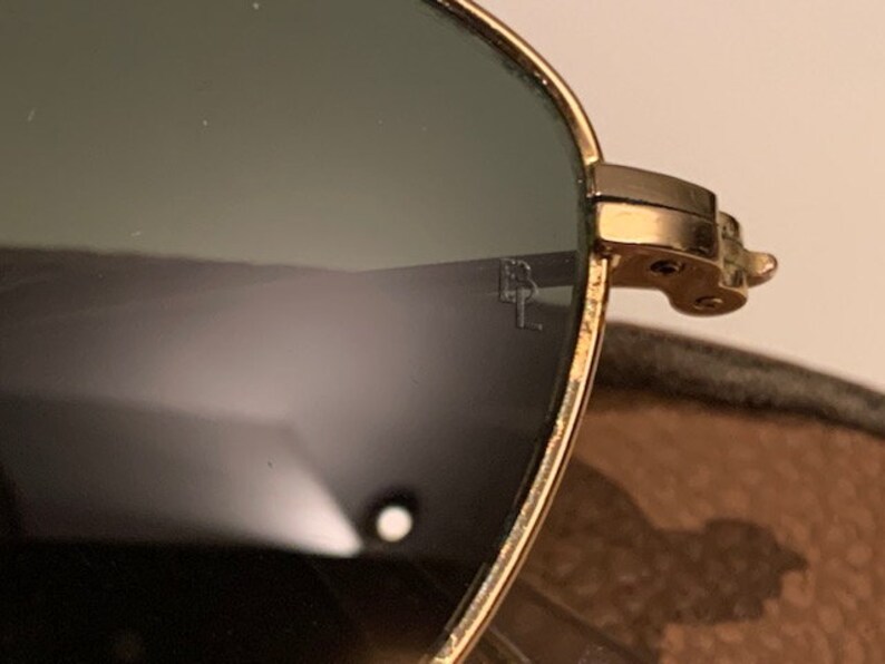 Peut inclure: Lunettes de soleil aviateur dor&eacute;es avec des verres verts. Les lunettes ont une monture en m&eacute;tal et sont en bon &eacute;tat.