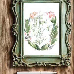 May include: A framed watercolour painting with a green and pink floral wreath surrounding the text "Fairest Lord Jesus, Ruler of all nature".