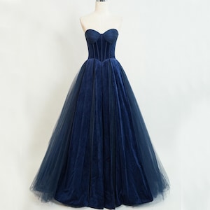 May include: A strapless navy blue velvet gown with a fitted bodice and a full tulle skirt.