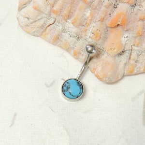 May include: A silver belly button ring with a turquoise stone.