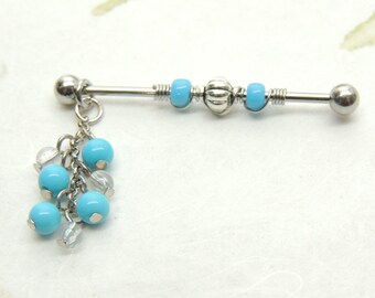 May include: A silver barbell with a dangling charm of blue and clear beads. The barbell has a silver ball on each end and three blue beads in the middle.