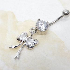 May include: Silver belly button ring with a clear crystal bow charm and a clear crystal top.
