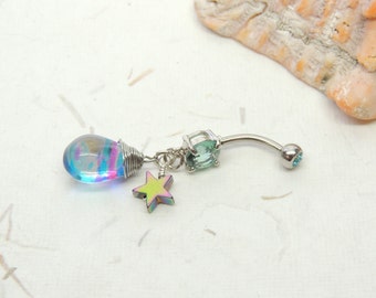 May include: A belly button ring with a curved, silver-colored barbell. It features a teardrop-shaped charm with iridescent colors, a light green gem, and a small, iridescent star charm. The end ball is light blue.