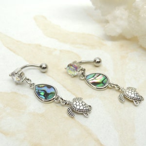 May include: A pair of silver belly button rings with a clear gem, a teardrop-shaped abalone shell, and a small turtle charm.
