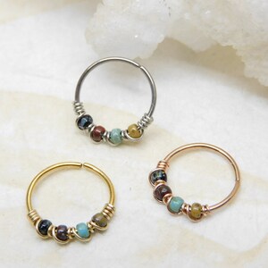 May include: Three hoop earrings with colourful beads. The hoops are made of silver, gold, and rose gold. The beads are a mix of turquoise, brown, and black.