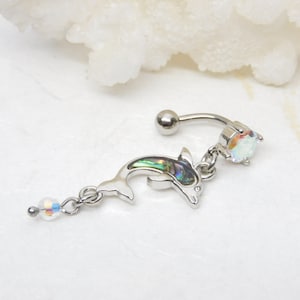 May include: A silver belly button ring with a dangling dolphin charm. The dolphin is made of iridescent abalone shell and has a clear crystal on the top. The ring has a clear crystal ball on the end.