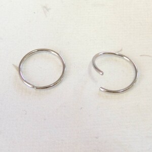 May include: Two silver hoop earrings, one is open and the other is closed.