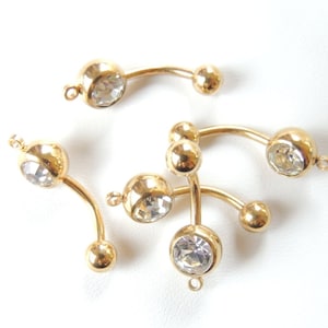 May include: Five gold belly button rings with clear crystal stones. The rings are curved and have a ball on each end.