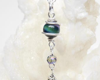May include: A silver chain necklace with a dark green and purple iridescent bead, a clear crystal bead, and a silver star charm.