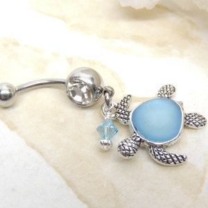 May include: A silver belly button ring with a clear crystal charm and a blue sea glass turtle charm.