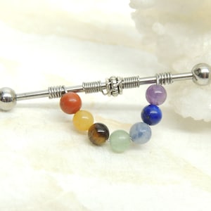 May include: A stainless steel barbell with a rainbow of gemstone beads. The beads are red, orange, yellow, green, blue, and purple. The barbell is a popular choice for body piercings.