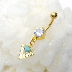 May include: Gold belly button ring with a clear crystal and a dangling turquoise triangle charm.