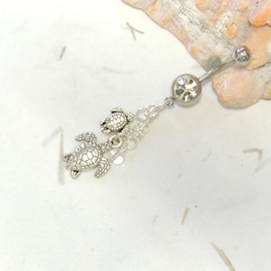May include: Silver belly button ring with a clear crystal charm and two silver turtle charms dangling from a silver chain.