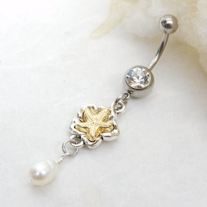 May include: Silver belly button ring with a clear crystal charm, a gold starfish charm, and a white pearl dangle.