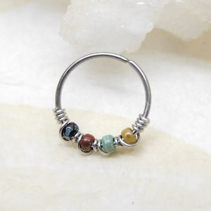 May include: A silver hoop earring with a beaded design. The beads are in shades of black, brown, green, and yellow.