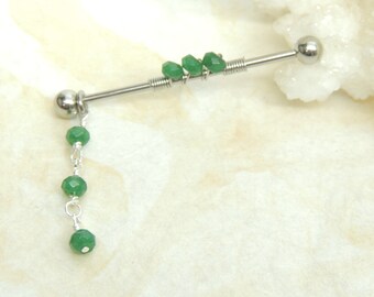 May include: A silver barbell with a green gemstone dangle. The barbell has a spring-like design and is adorned with multiple green gemstones.