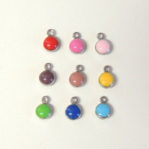 May include: Nine colourful round charms with silver-tone metal loops. The charms are in various colours, including red, pink, light pink, brown, peach, yellow, green, blue, and turquoise. Each charm has a glossy finish.