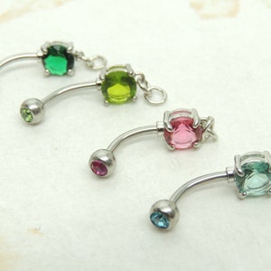 May include: Four belly button rings with different colored gems. The gems are green, light green, pink, and blue.