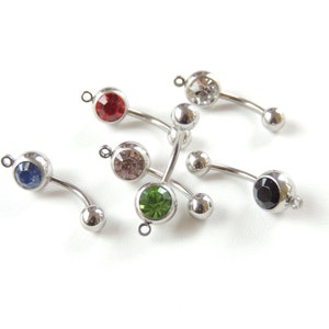 May include: A collection of curved, silver-toned belly button rings with colorful gemstone accents. The rings feature a variety of jewel tones, including red, blue, green, pink, clear, and black. Each ring has a small loop at the top for easy attachment.