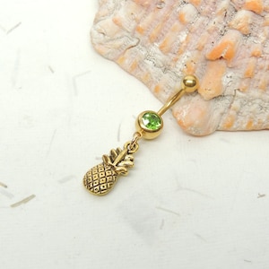 May include: Gold body jewelry with a green gem and a pineapple charm.
