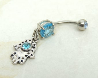 May include: A silver belly button ring with a blue crystal charm and a hamsa hand charm with a blue crystal in the center.