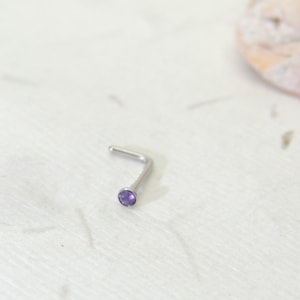 May include: A silver nose ring with a small, round, purple gemstone.