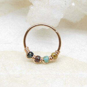 May include: A gold hoop earring with a beaded design. The beads are brown, black, turquoise, and green.