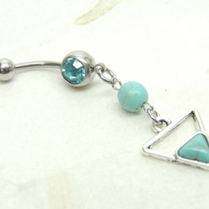 May include: A silver belly button ring with a turquoise gem and a dangling turquoise bead and triangle charm.
