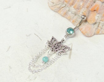 May include: Silver body jewelry with a lotus flower charm and turquoise bead. The charm has an Om symbol in the center. The jewelry is attached to a chain with multiple strands.