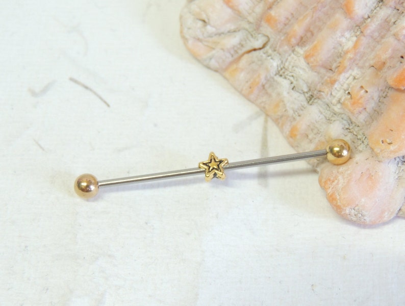 May include: A gold star barbell with two gold balls on either end. The barbell is made of surgical steel and is suitable for body piercing.