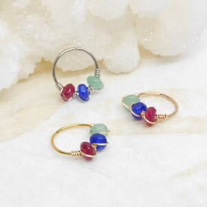 May include: Three hoop earrings with three beads each. The beads are green, blue, and red. The hoops are silver, gold, and rose gold.