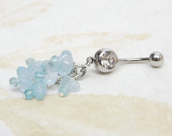 May include: A silver belly button ring with a clear crystal charm and a dangle of light blue aquamarine stones.
