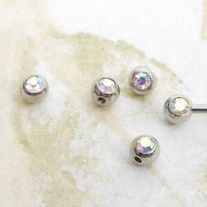 May include: Five silver-toned body jewellery balls with iridescent rhinestones. The balls are approximately 5mm in diameter.