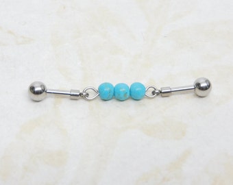 May include: A silver barbell with three turquoise beads. The barbell is a body piercing jewelry item.