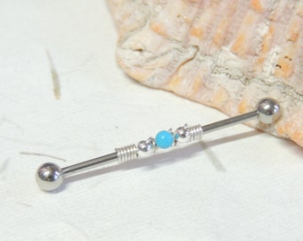 May include: A silver barbell with a turquoise bead and silver beads. The barbell is on a white surface.